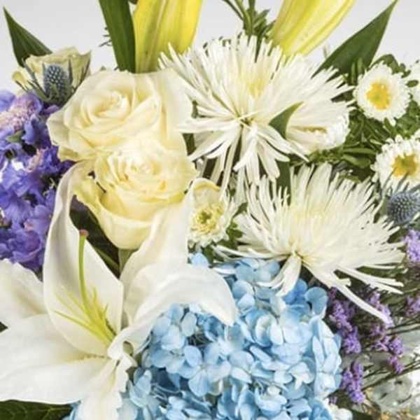 Bouquet of white lilies, cream roses, blue hydrangea, and purple flowers