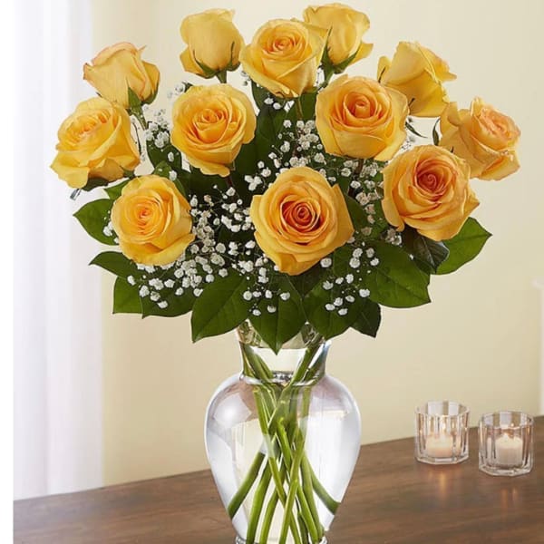 Yellow roses arranged in a clear glass vase with baby's breath