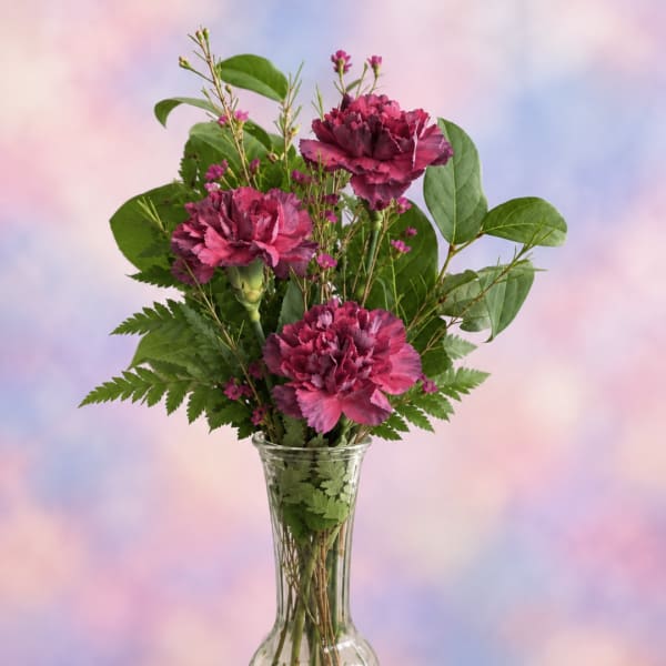 Pink carnations in a clear glass vase with mixed greenery
