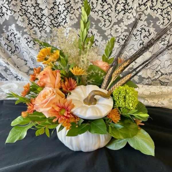Pumpkin-shaped floral arrangement with peach roses and orange mums