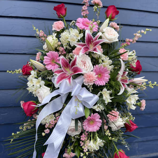 Large pink and white floral spray with a white ribbon bow