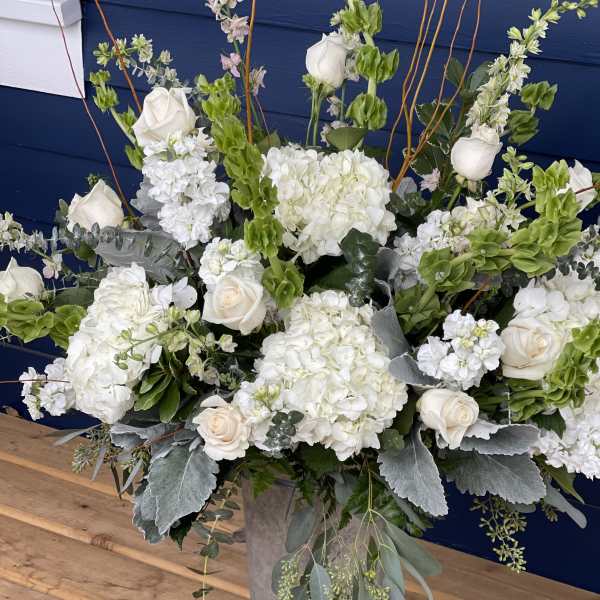 White roses and hydrangeas in a tall metal vase