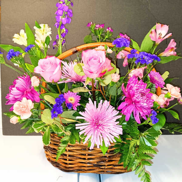 Basket arrangement of pink roses, chrysanthemums, and mixed blooms