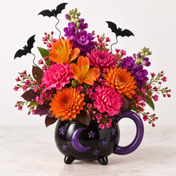 Bright orange, pink, and purple flowers in a black Halloween mug with bat picks