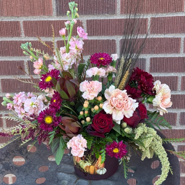 Mixed bouquet in a decorated vase with roses, carnations, and magenta daisies