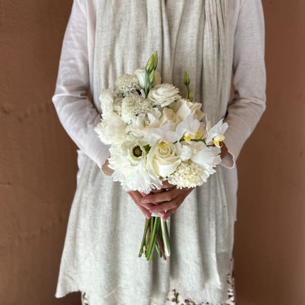 Bride holding a white bouquet with roses and orchids