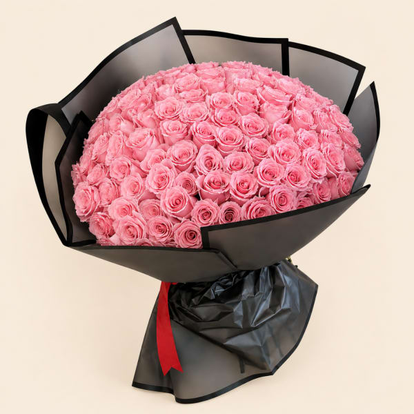 Large bouquet of pink roses wrapped in black paper with a red ribbon