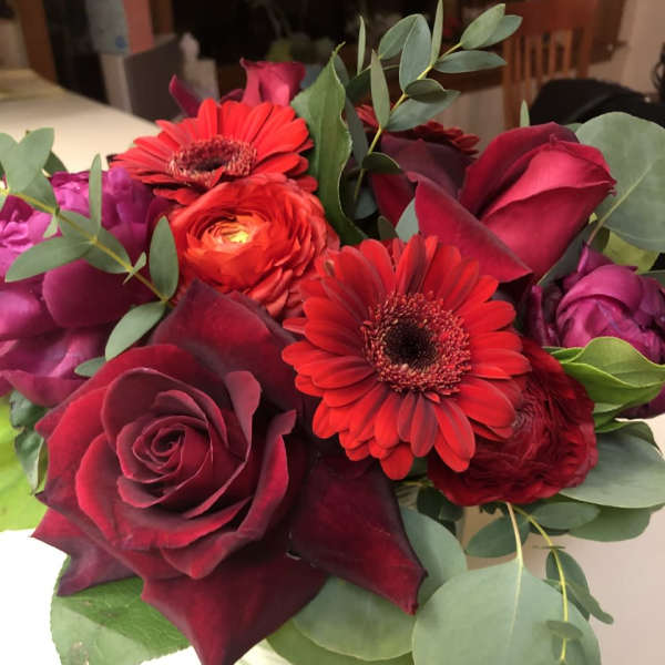 Bouquet of red roses and gerbera daisies in a glass vase