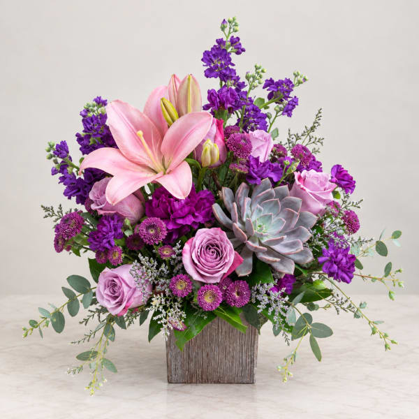 Pink lilies and roses with purple flowers in a wooden vase