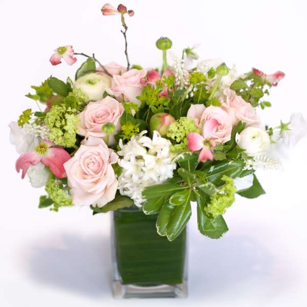 Pink roses and white blooms arranged in a square glass vase