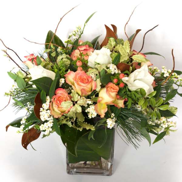 Peach and white roses in a square glass vase with mixed greenery