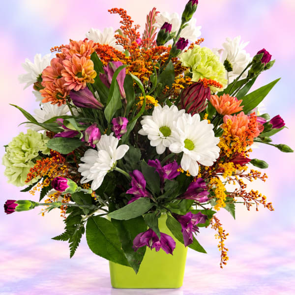 Mixed bouquet of daisies, carnations, and purple blooms in a lime green vase