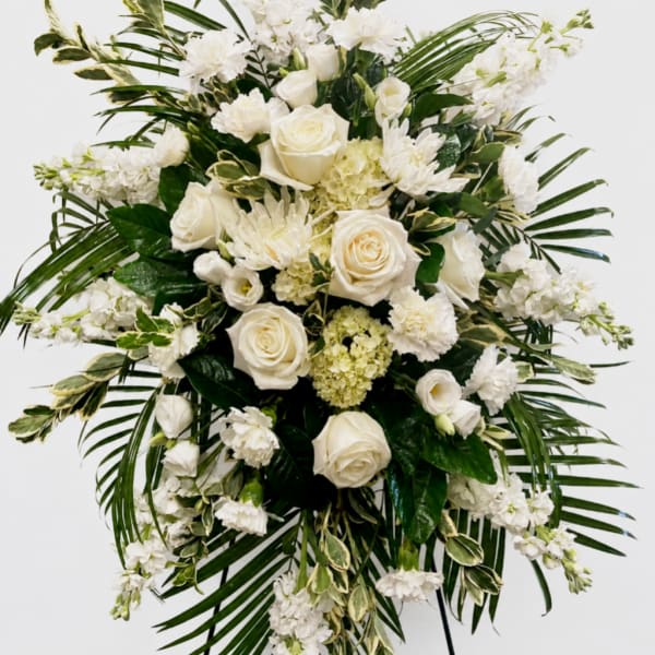 White rose and carnation arrangement with palm fronds on a stand