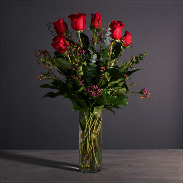 Red roses in a clear glass vase with small pink filler flowers