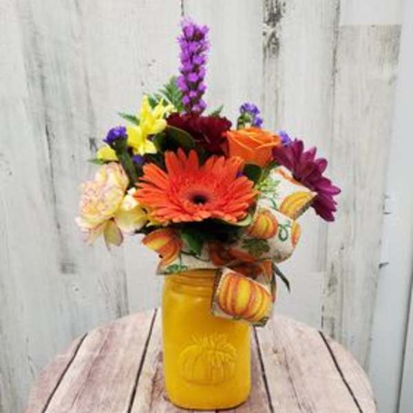 Colorful mixed flower arrangement in a yellow mason jar