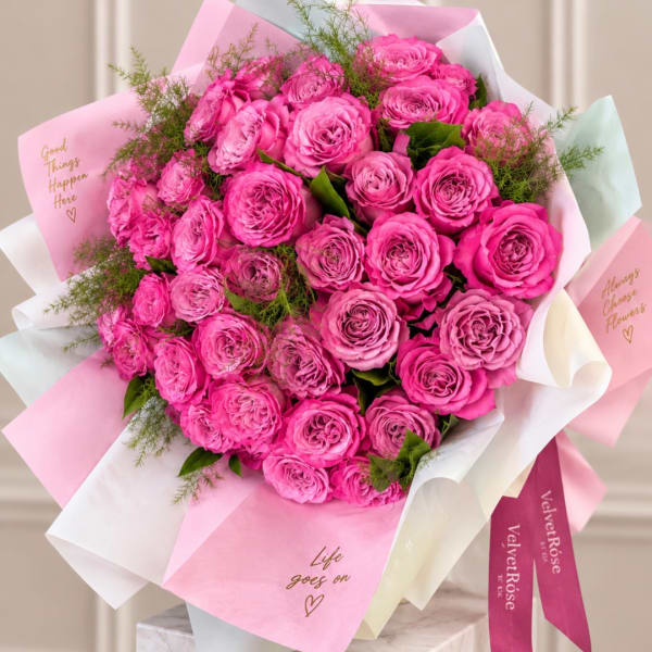 Bouquet of bright pink roses wrapped in pink and white paper