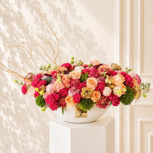 Mixed pink and peach flower arrangement in a white bowl vase