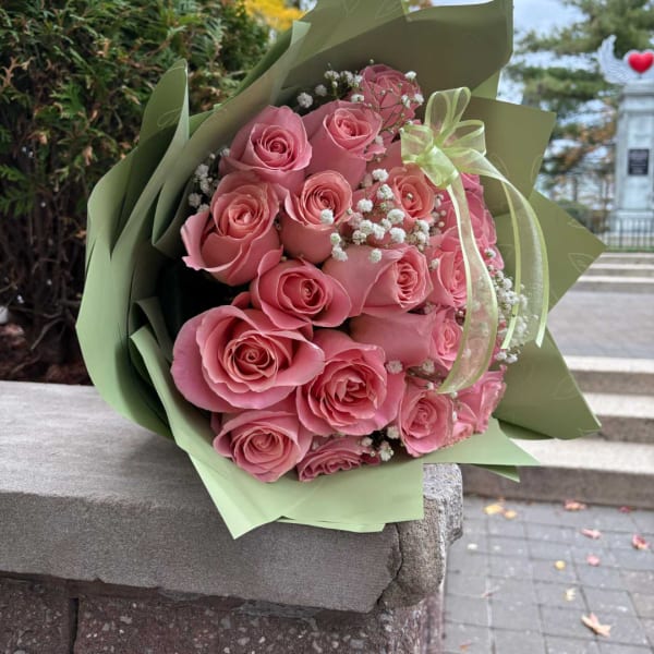 Pink rose bouquet wrapped in pale green paper with a ribbon