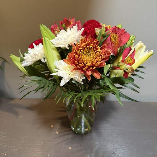 Mixed bouquet of chrysanthemums and lilies in a glass vase
