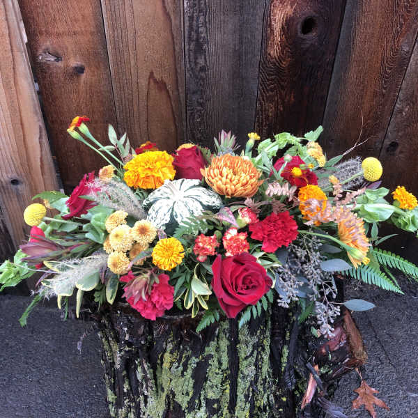 Mixed floral arrangement with roses, carnations, and mums in a rustic container