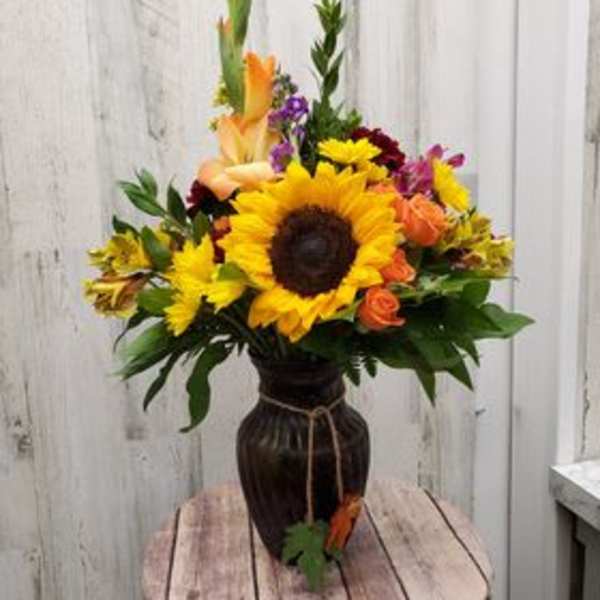 Sunflower and mixed flower arrangement in a dark vase