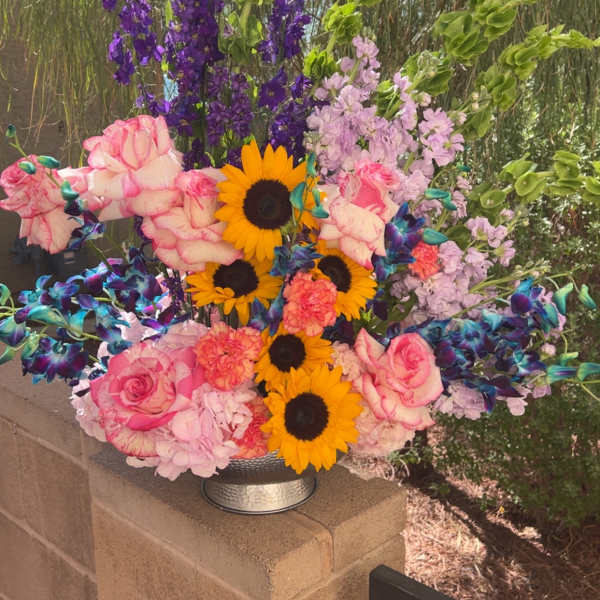Colorful bouquet with sunflowers, pink roses, and purple blooms in a silver vase