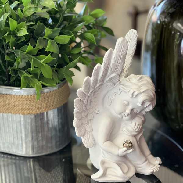 White angel figurine beside a potted green plant