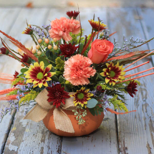 Colorful floral arrangement in a small orange pot with a burlap bow