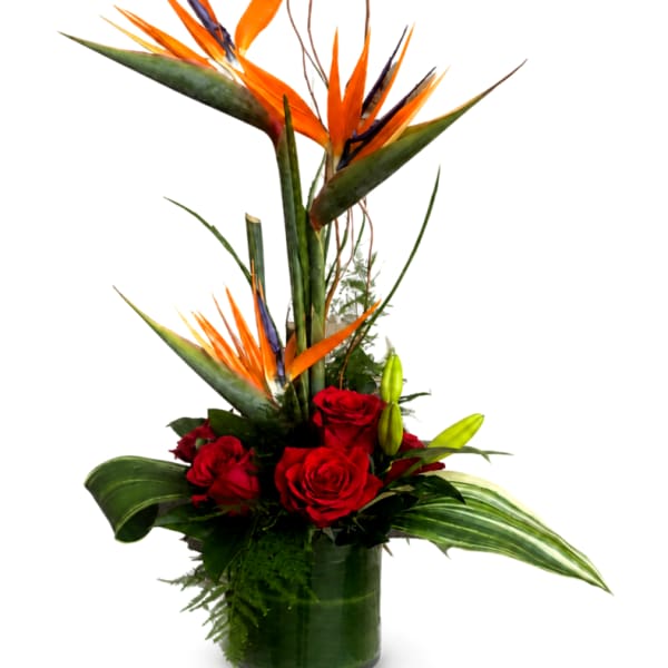 Tall tropical arrangement with red roses in a glass vase