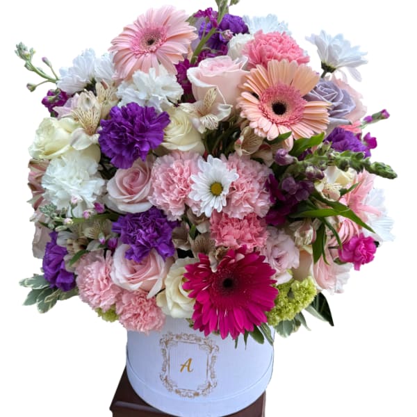 Mixed pink, white, and purple flowers arranged in a white hat box