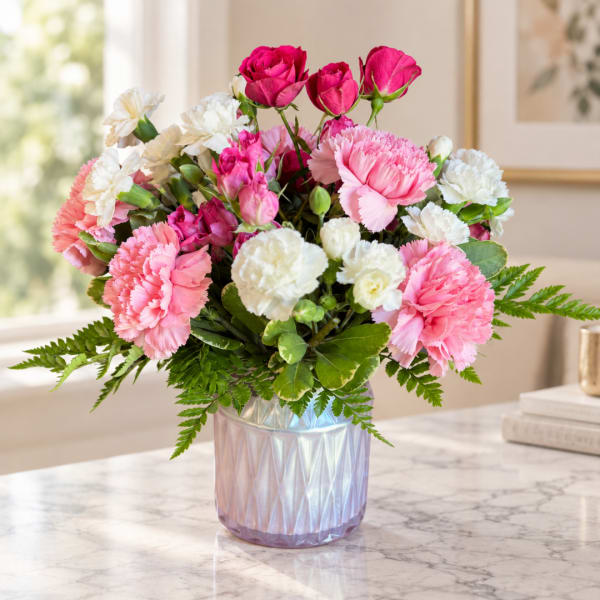 Pink and white carnations with roses in an iridescent vase