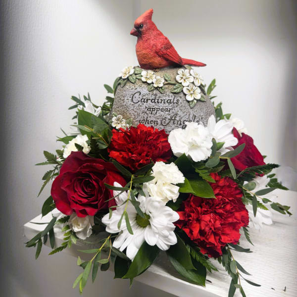 Red cardinal figurine above a red, white, and green floral arrangement