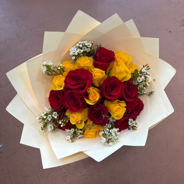 Bouquet of red and yellow roses wrapped in cream paper