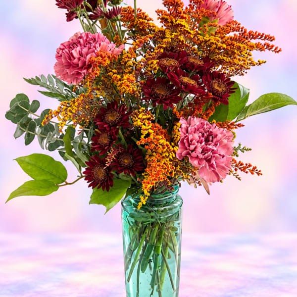 Mixed bouquet of pink and burgundy flowers in a glass vase