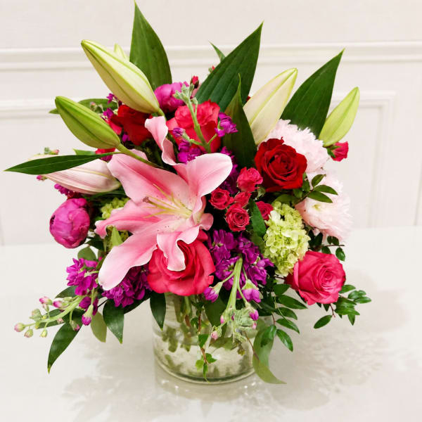 Pink lilies and roses arranged in a clear glass vase
