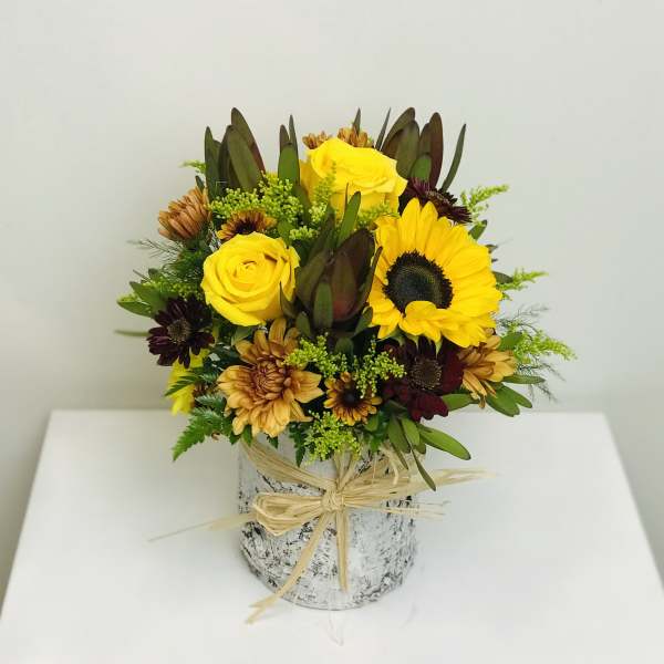 Yellow roses and sunflowers in a rustic wrapped vase arrangement