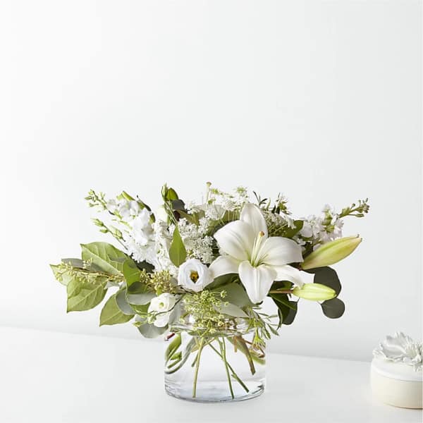 White lily and mixed white flowers in a clear glass vase