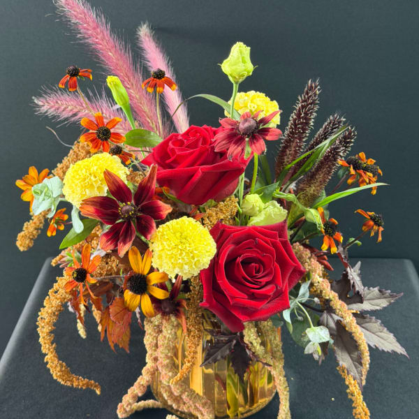 Red roses and mixed fall flowers in a glass vase