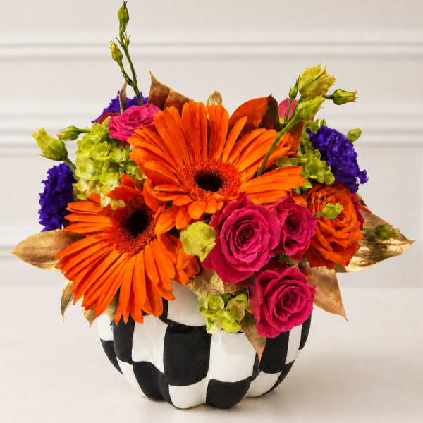 Bright orange gerbera and pink roses in a black-and-white checkered pumpkin container
