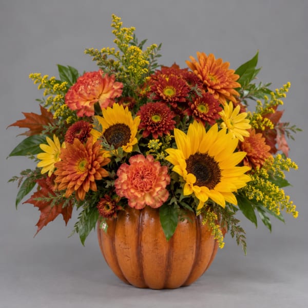 Autumn bouquet in a pumpkin-shaped container with sunflowers and mums