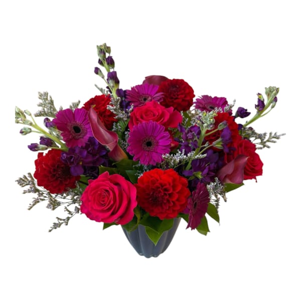 Mixed bouquet of pink, red, and purple flowers in a dark vase