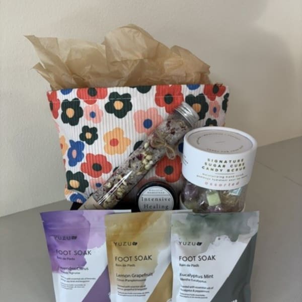 Gift basket with candy, a floral-patterned bag, and foot soak packets