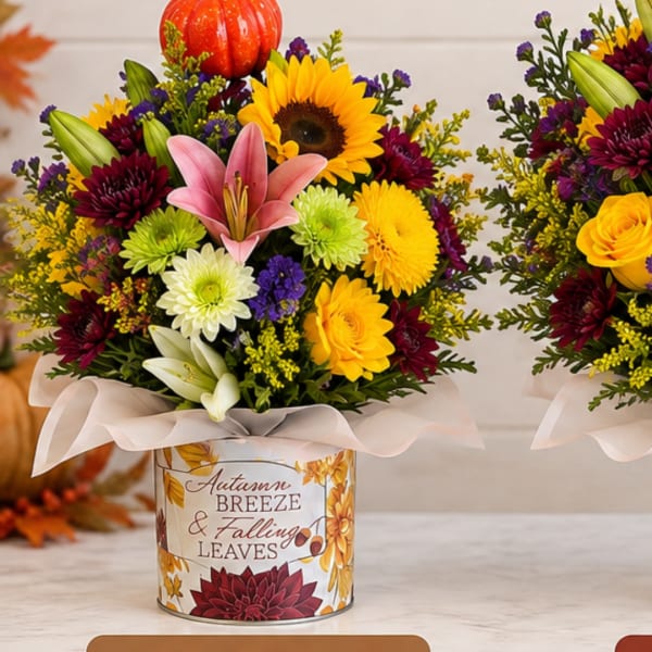 Autumn flower arrangement in a decorated tin container with a ribbon bow