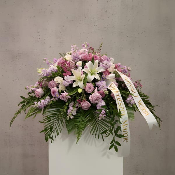 Lavender and white floral spray with ribbon on a pedestal