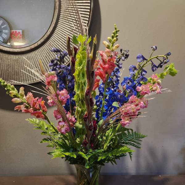 Tall mixed bouquet in a glass vase with blue and pink flowers