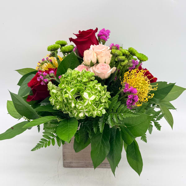 Mixed bouquet of red and blush roses with green hydrangea in a wooden box