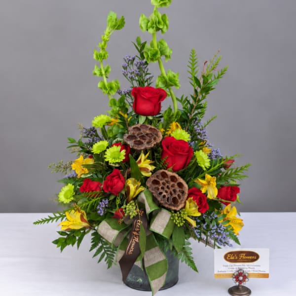 Tall mixed flower arrangement with red roses and yellow blooms in a vase