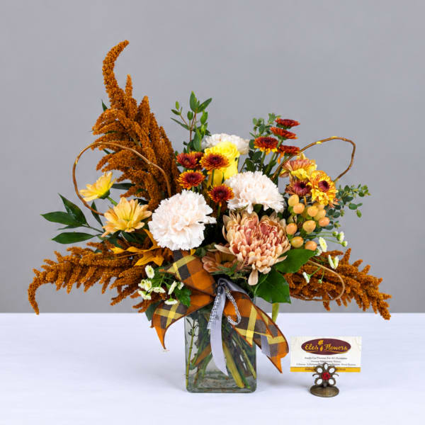 Autumn bouquet in a glass vase with mums, carnations, and orange filler flowers