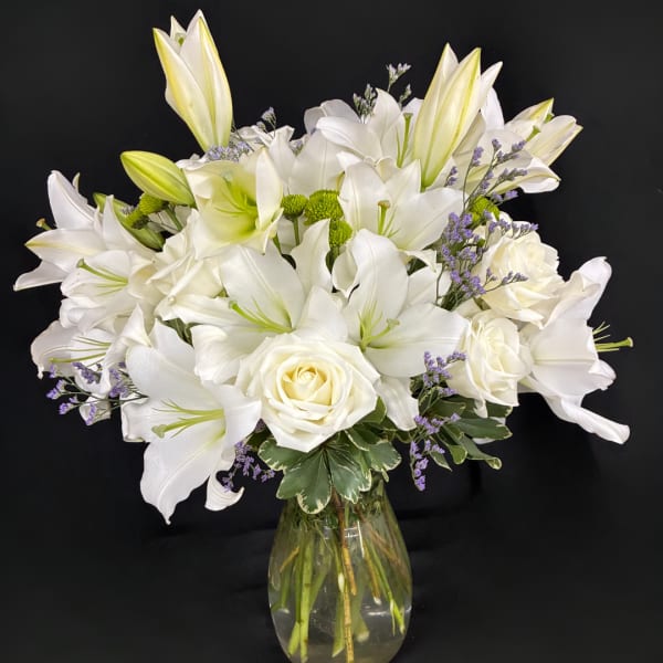 White lilies and roses arranged in a glass vase