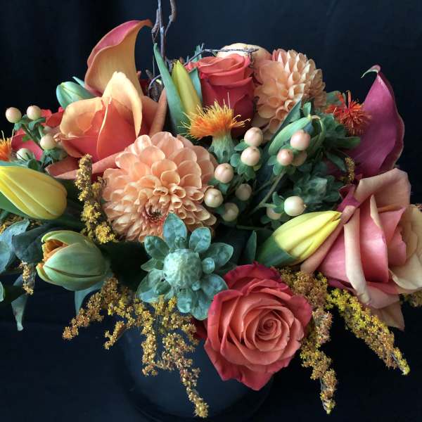 Mixed bouquet with roses, calla lilies, dahlias, and tulips in a dark vase